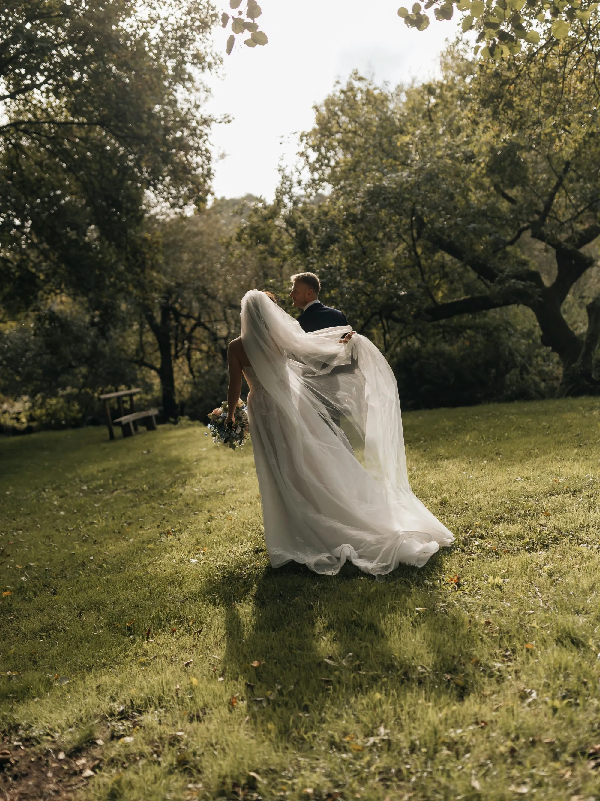 Un couple de mariés partageant un moment intime dans un parc luxuriant.
