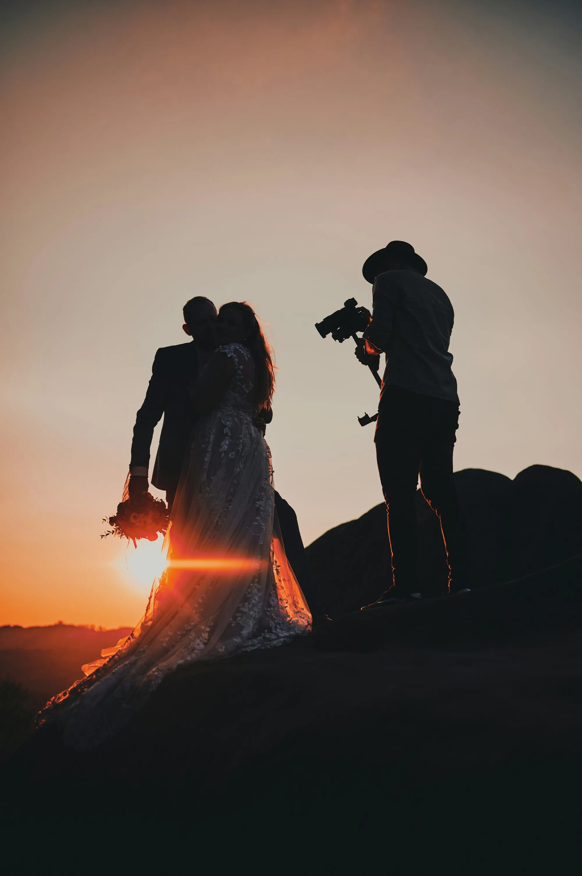 Couple romantique à l'ombre du coucher de soleil, capturant l'ambiance magique d'une célébration de mariage.