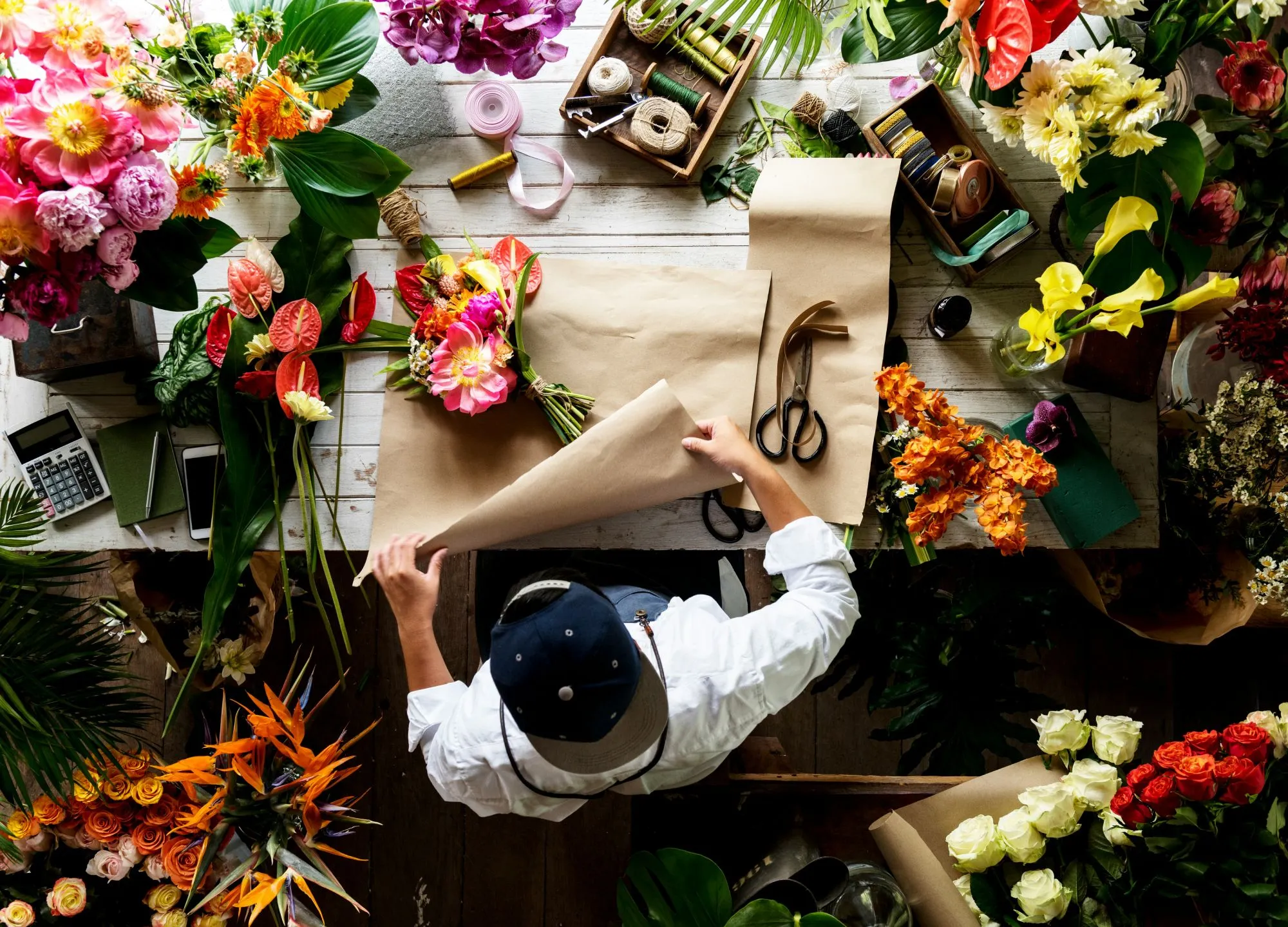 Un artisan fleuriste crée des compositions florales artisanales dans un espace créatif rempli de fleurs colorées et de