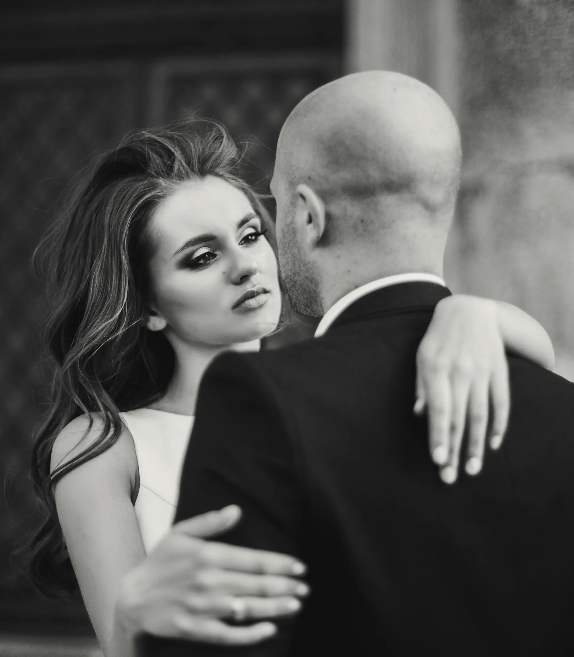 Un couple romantique partage un moment tendre dans un décor élégant, capturé en noir et blanc.