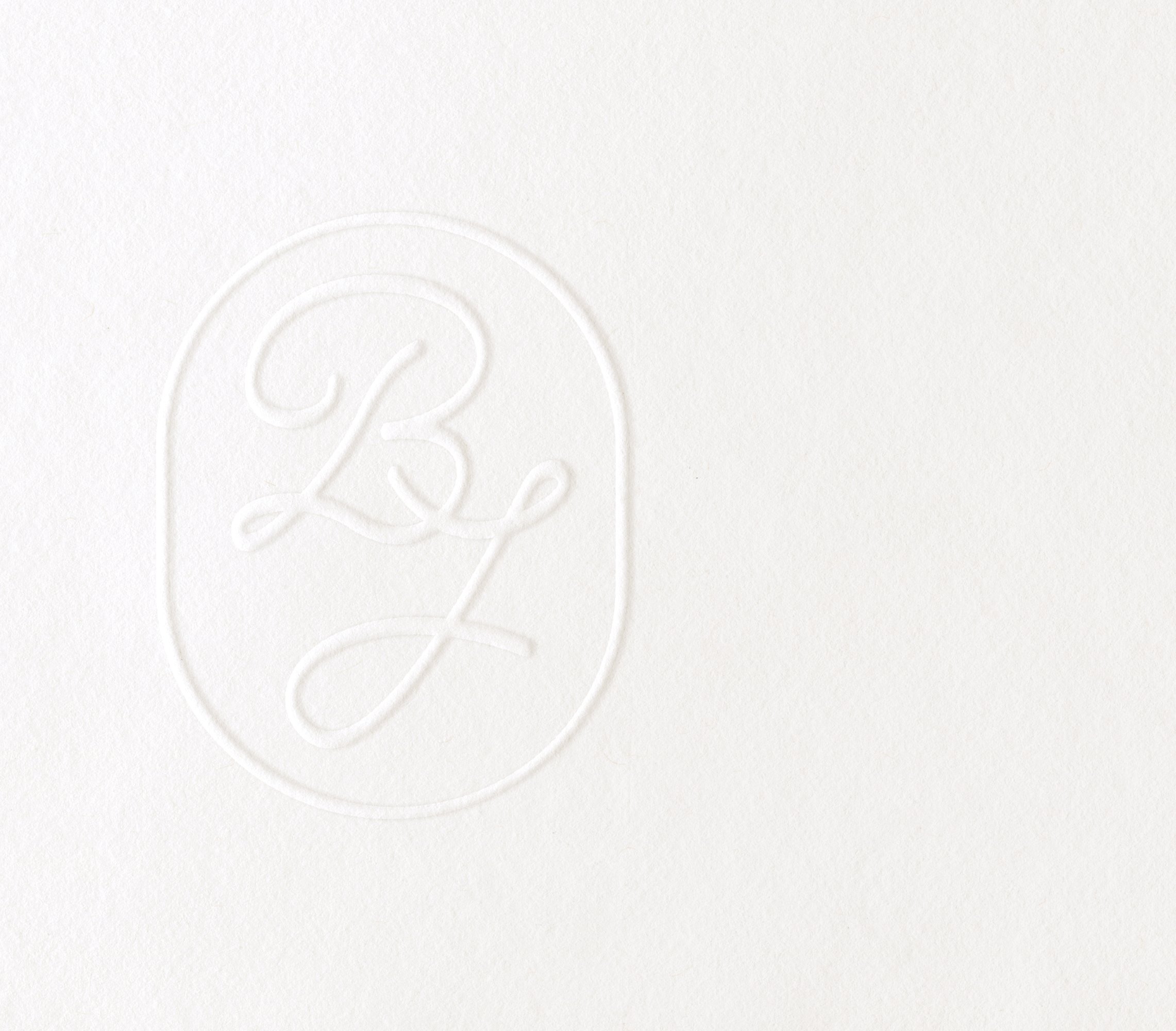 Un monogramme élégant et subtil imprimé sur du papier blanc, idéal pour une invitation de mariage classique.
