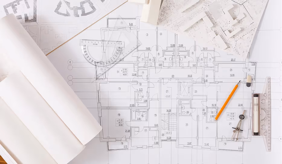 Architectuur blauwdruk met potlood, passer, linialen en papieren modellen op bureau.