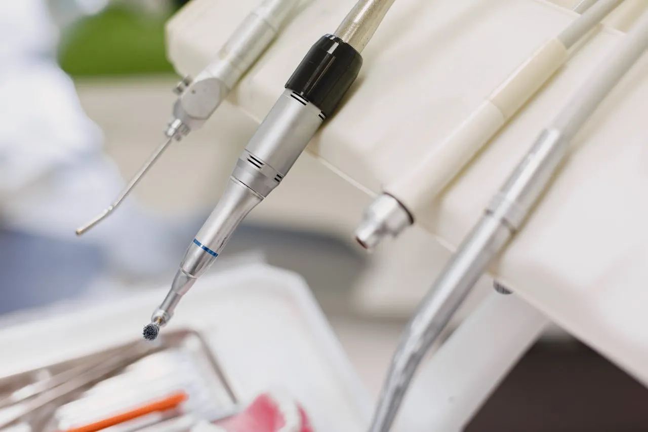 Close-up of dental tools, including a rotary brush handpiece on a dental unit.
