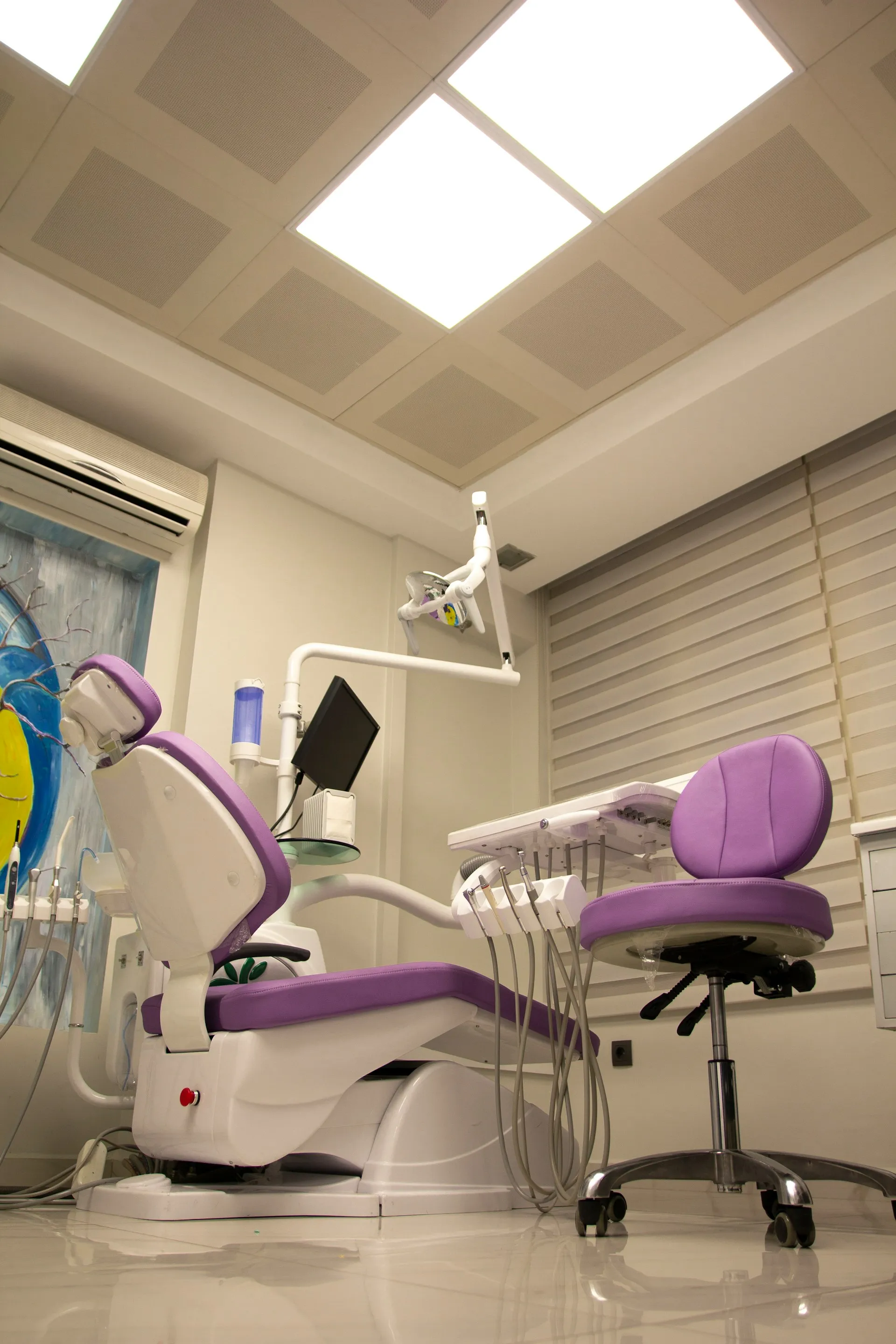 Purple dental chair and matching dentist stool in a clean modern dental clinic room.