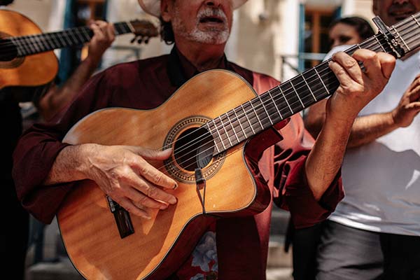 Musicien en chemise bordeaux jouant de la guitare espagnole lors d'un mariage à l'ambiance bohème.