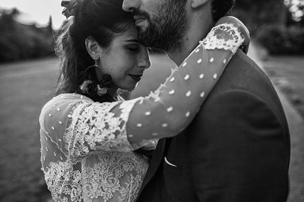 Couple enlacé en noir et blanc, la mariée portant une robe en dentelle bohème, ambiance romantique et intime.
