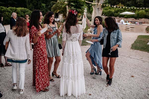 Groupe d'invitées élégantes discutant en extérieur lors d'un mariage bohème à l'ambiance festive et décontractée.