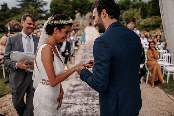 Jeune couple s'échangeant les alliances lors d'une cérémonie bohème en extérieur, entouré de leurs invités.