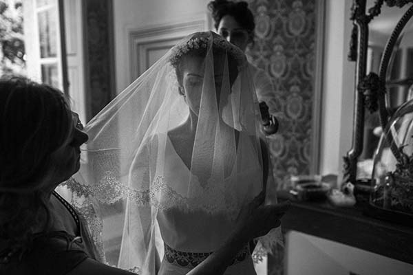 Mariée voilée en noir et blanc, entourée de ses proches dans une ambiance intime et élégante.