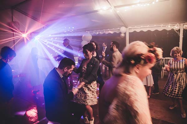 Invités dansant sous des jeux de lumières colorées lors d'une soirée de mariage festive et dynamique.