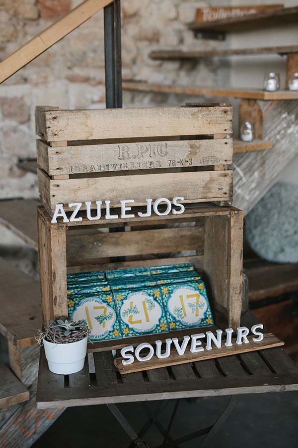 Casiers en bois rustiques présentant des azulejos colorés et des souvenirs pour un mariage à l'ambiance décontractée.