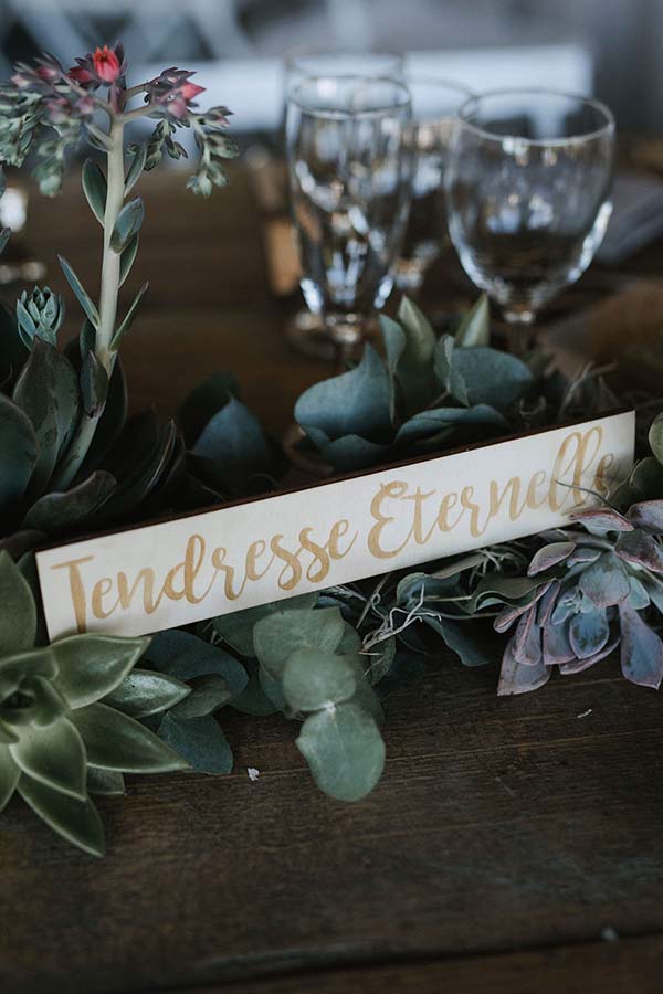 Décoration de table champêtre avec succulentes et un panneau doré indiquant Tendresse Éternelle sur bois sombre.