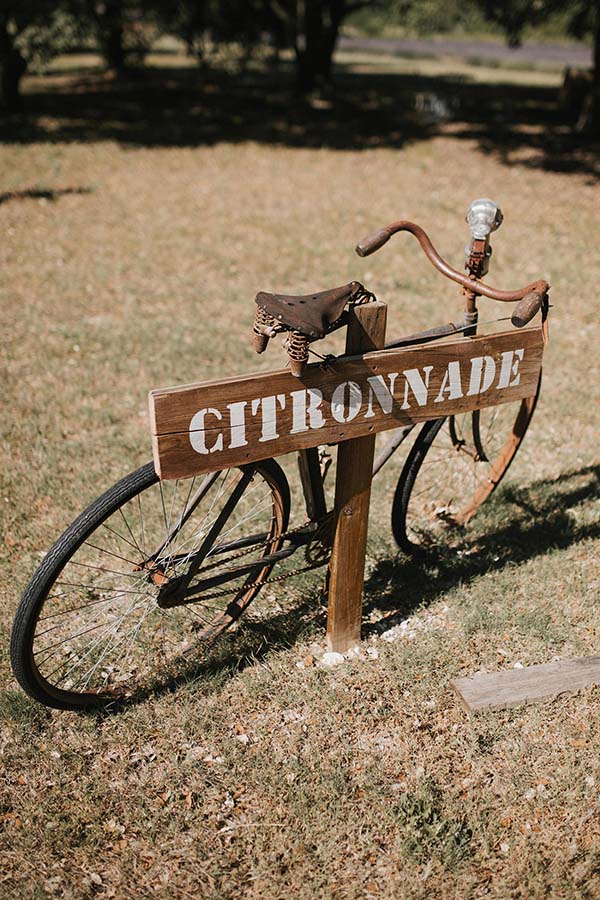 Vélo vintage avec un panneau Citronnade en bois, décor champêtre et ensoleillé pour un mariage.