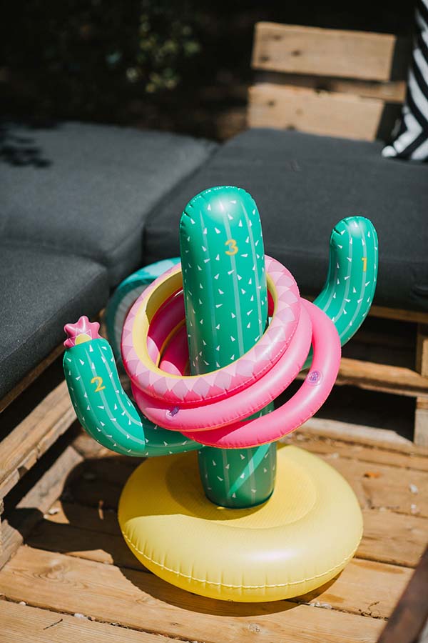 Jeu de lancer d'anneaux colorés sur un cactus gonflable posé sur une table en bois pour un mariage décontracté.