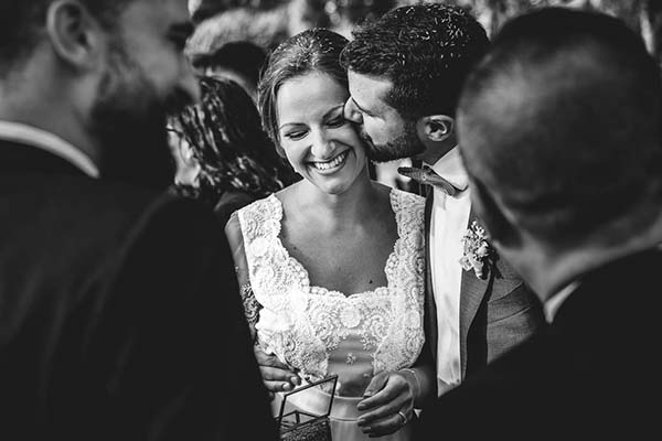 Photo noir et blanc d'un marié embrassant tendrement la joue de sa mariée souriante lors de leur mariage.