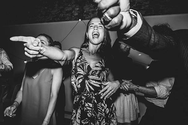 Invités en liesse dansant avec enthousiasme lors d'une soirée de mariage, cliché noir et blanc dynamique.