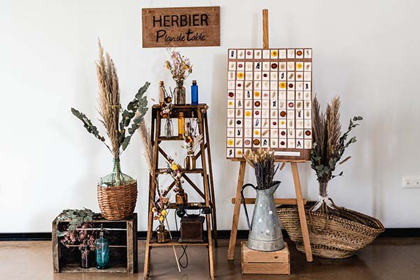 Plan de table champêtre avec herbiers, fleurs séchées et accessoires en bois et osier dans des tons naturels.