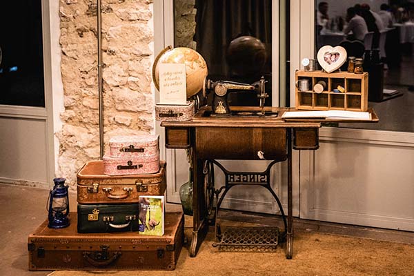Décoration vintage avec machine à coudre, valises anciennes et globe terrestre dans des tons bruns et beiges.