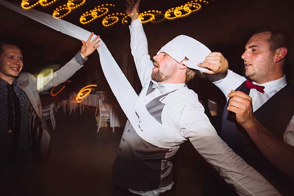 Invités en tenue de fête s'amusant avec un long ruban blanc lors d'une soirée de mariage dynamique.