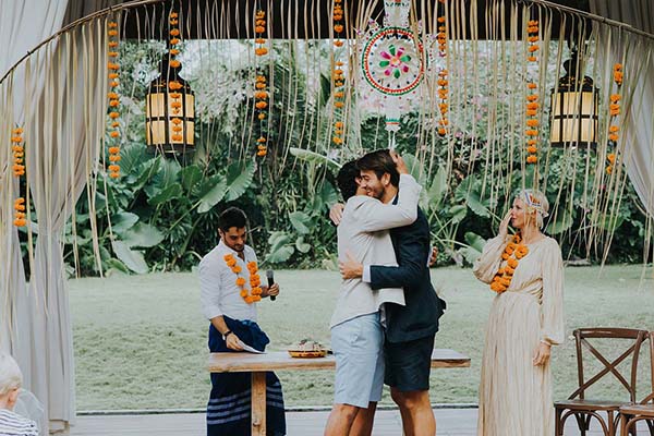 Couple s'enlaçant lors d'un renouvellement de vœux à Bali, sous une arche décorée de fleurs et de lanternes.