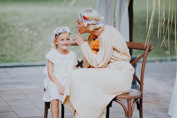Une femme et une petite fille en robes blanches et accessoires floraux partagent un moment complice à Bali.