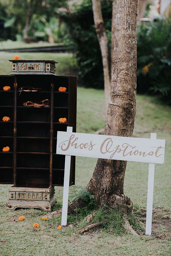 Meuble à chaussures vintage et panneau Shoes Optional sous un arbre pour un mariage bohème à Bali.