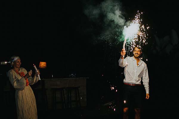 Couple célébrant leur renouvellement de vœux la nuit avec des feux de Bengale étincelants sur un fond sombre.