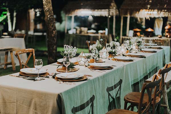 Table de réception élégante aux tons blanc et vert d'eau, décorée de fleurs et bougies pour un dîner romantique à Bali.