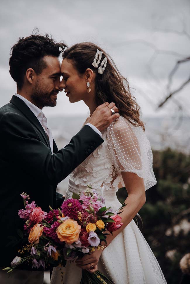 Un couple romantique se penche l'un contre l'autre, entouré de fleurs vives, dans un décor époustouflant.