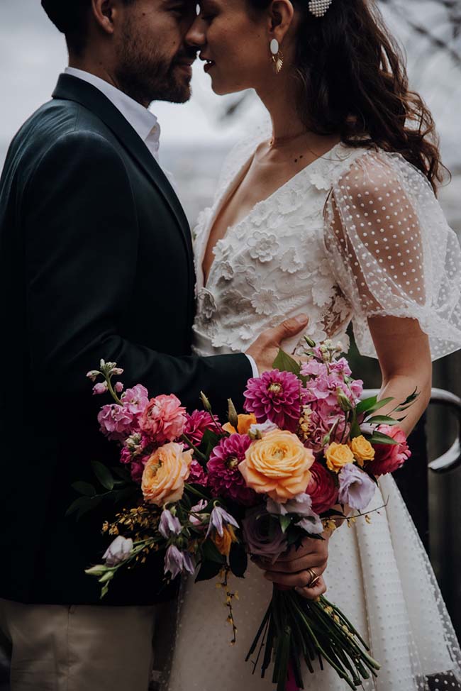 Un couple romantique se penche l'un envers l'autre, tenant un bouquet coloré de fleurs, incarnant l'ambiance romantique