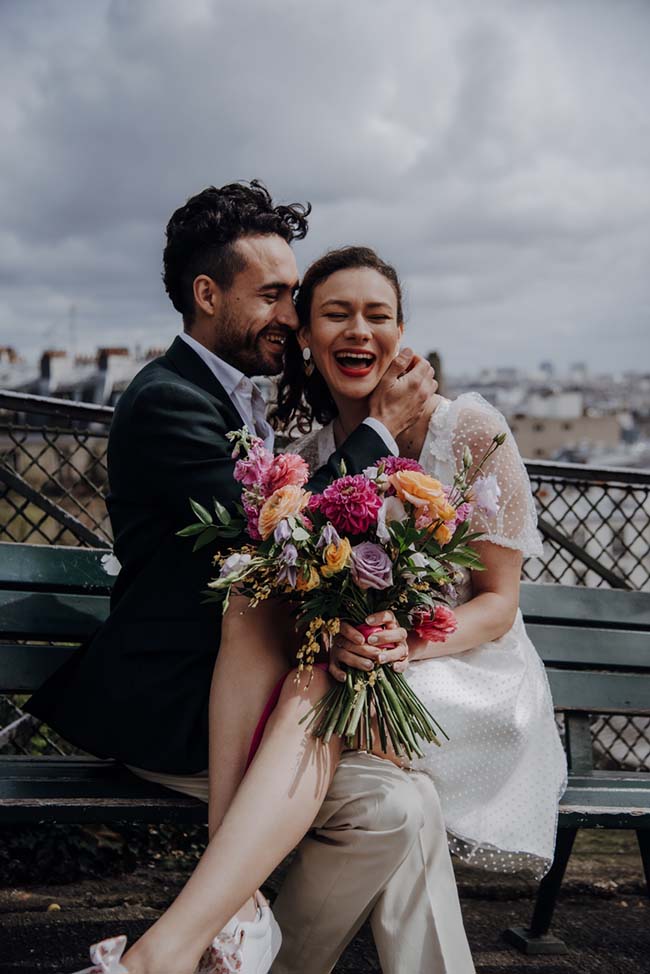 Un couple heureux partageant un moment tendre sur un pont, entouré de fleurs colorées, incarnant l'essence d'un