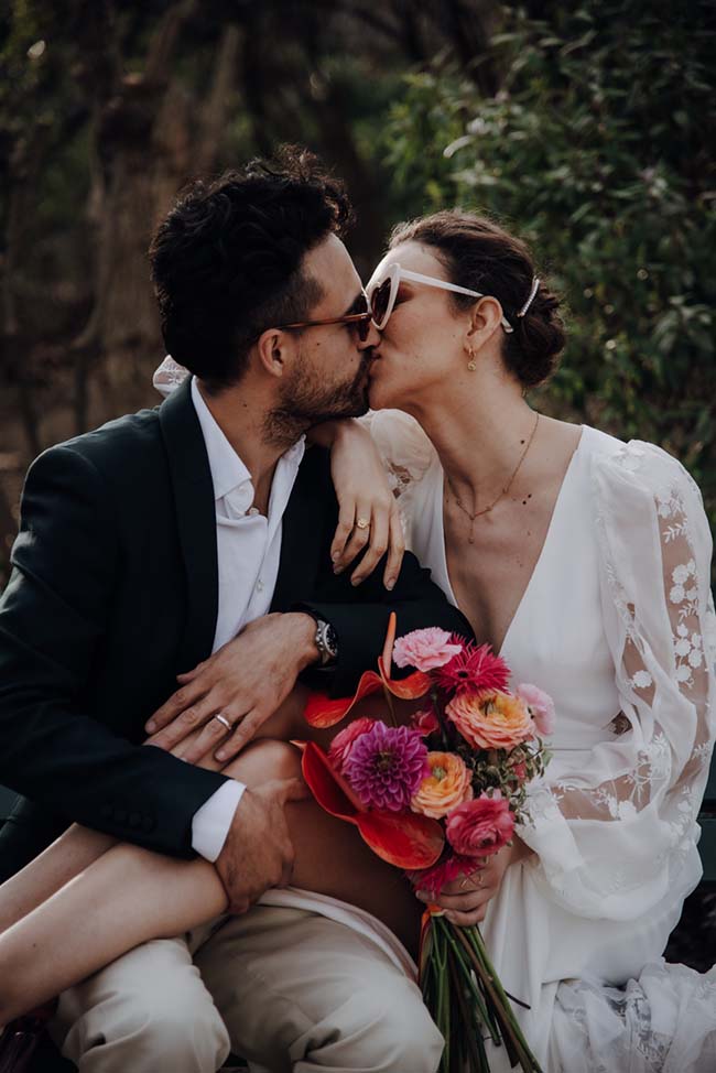 Un couple romantique partage un baiser tendre en plein air, entouré de fleurs colorées, incarnant l'essence d'un