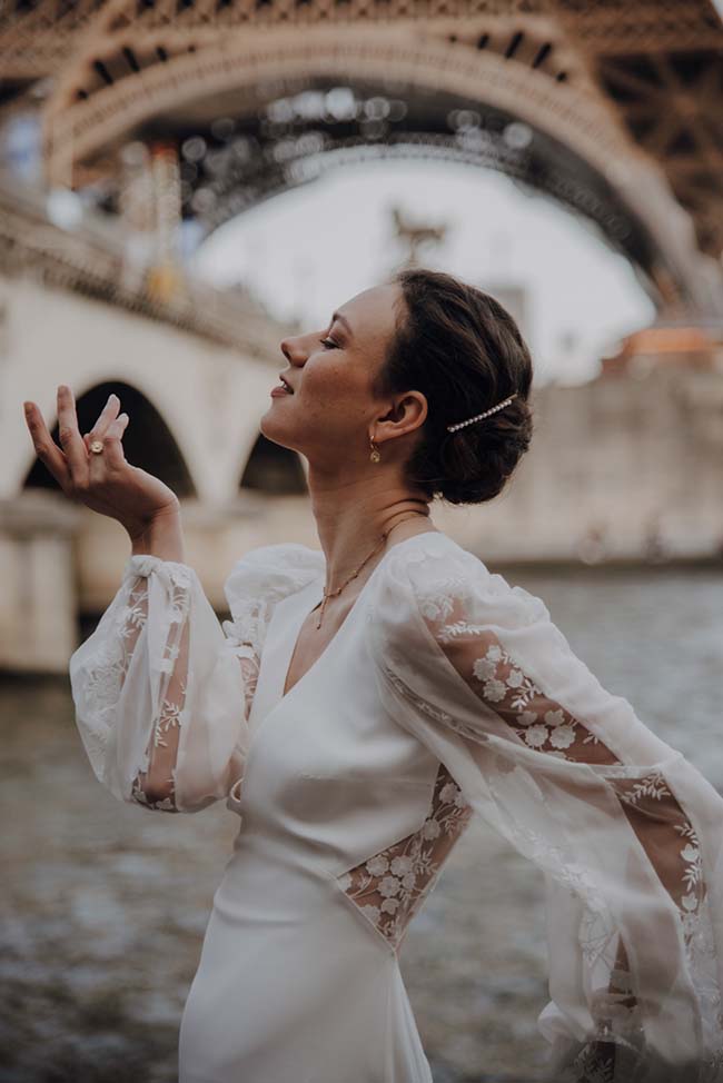 Une jeune mariée dans un robe blanche élégante se détend devant le Tour Eiffel, incarnant l'élégance romantique d'un