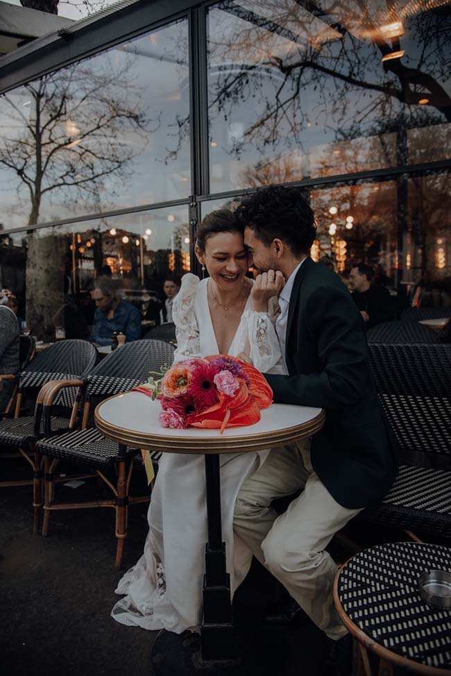 Un couple heureux partage un moment intime au sein d'un restaurant chic, son bouquet de fleurs colorés ajoutant un