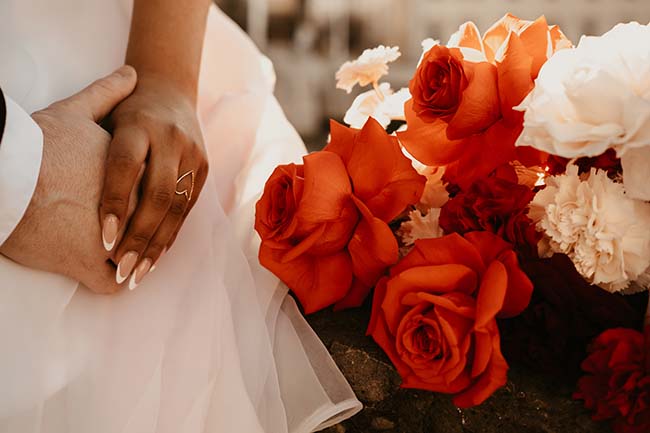 Un mariage urbain aux couleurs chaudes, avec des mains tendues et des roses rouges éclatantes.