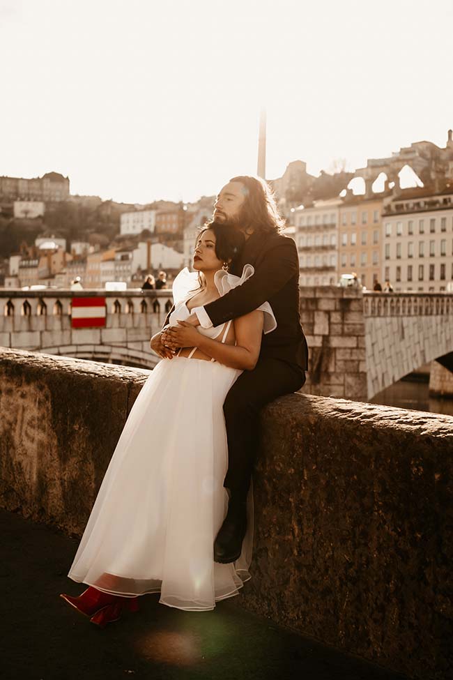 Un couple romantique se détache sur un pont urbain, ses couleurs chaudes suggérant un mariage urbain charmant.