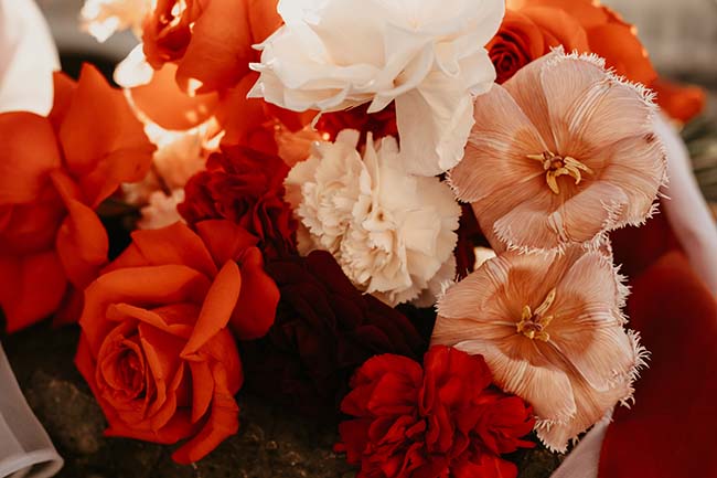 Magnifique bouquet urbain aux tons chauds, avec des roses rouges et des fleurs blanches et roses élégantes.