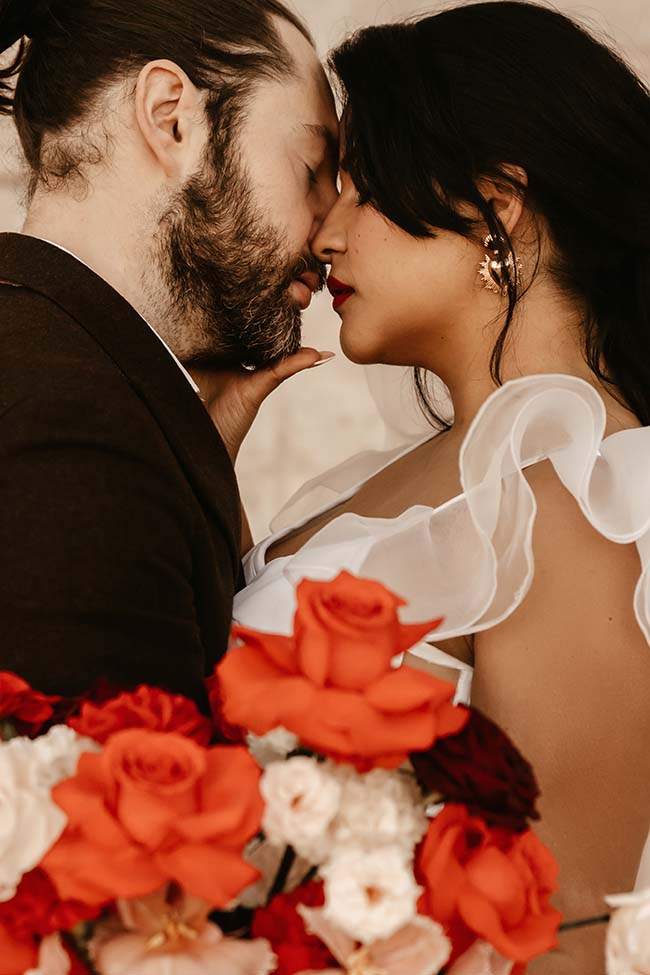 Un couple de mariés émouvants se penchent l'un contre l'autre, entourés de fleurs chaudes et romantiques.