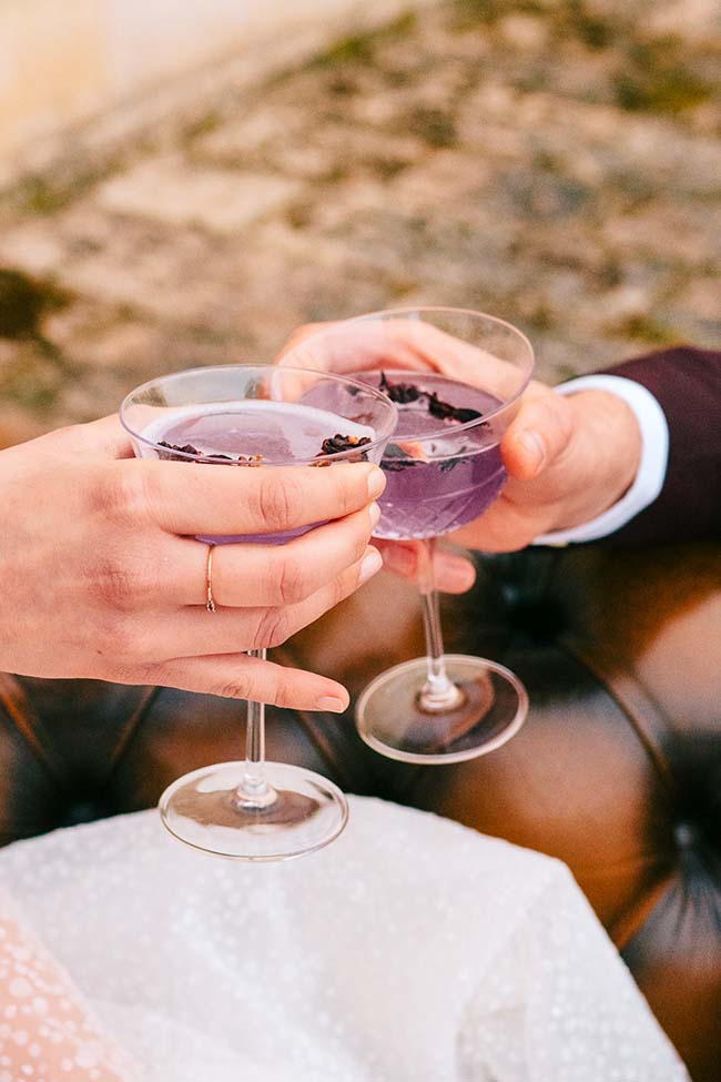 Coup d'oeil romantique avec des verres de vin violets, symbolisant l'harmonie et l'union d'un couple dans un décor de