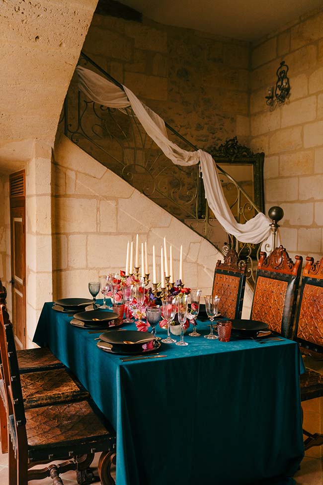Tableau de banquet luxueux dans un décor historique, avec un miroir orné et une escalier en verre, pour un mariage