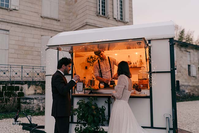 Un couple de mariée et de marié savoure un verre de vin chaud dans un camion de boissons chaleureux, renforcé par