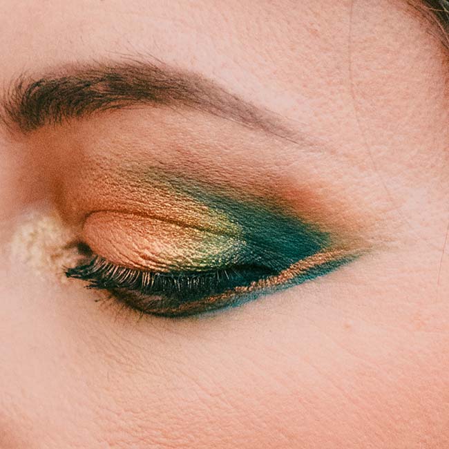 Un œil détaillé de maquillage élégant et audacieux, caractérisé par des tons de vert et d'or, met en valeur l'ambiance