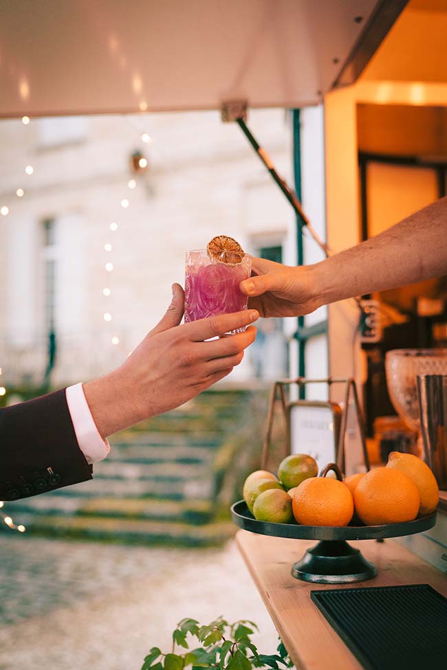 Un verre de cocktail coloré offert dans un bar chic, mettant en scène un ambiance animée et moderne.