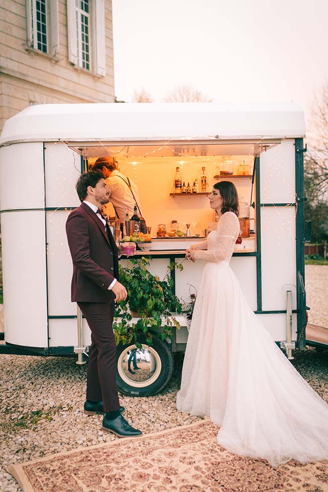 Un couple charmant se pose devant une camionnette de repas raffinée, évoquant un mariage chic et contemporain.