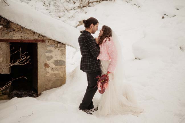 Un couple enlacé dans un moment intime, entouré d'un paysage enneigé charmant et romantique.