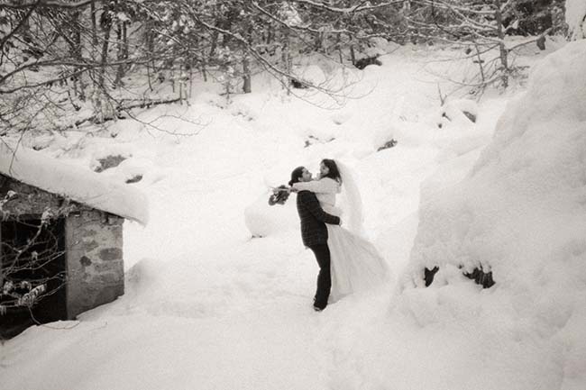 Un couple de mariée et de marié partageant un instant intime dans un décor neigeux, incarnant l'ambiance chaude et