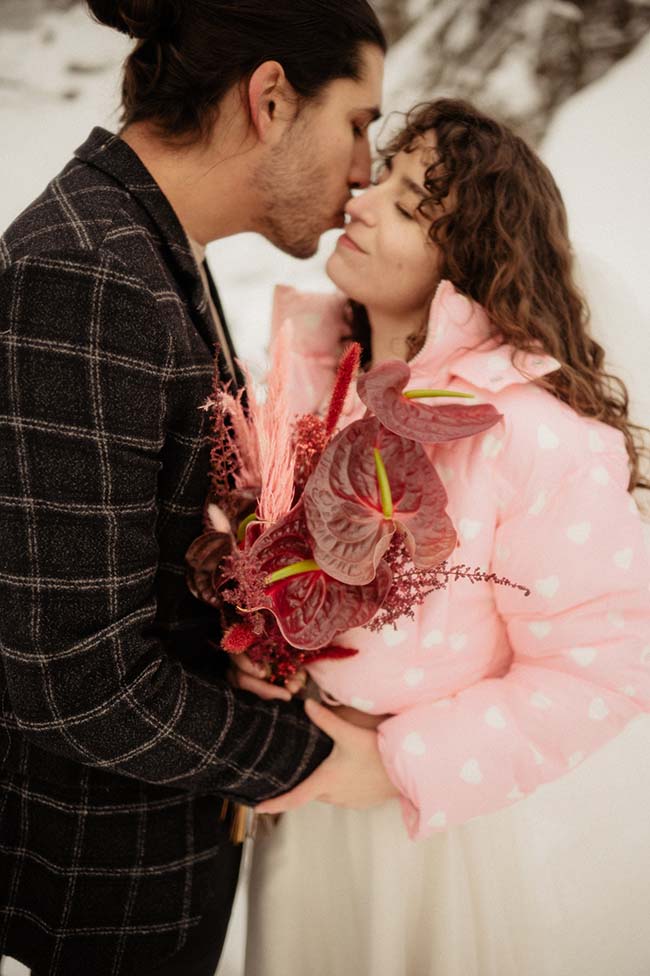 Un couple romantique partageant un moment intime au milieu de la neige, vêtu d'une robe de neige rose douce et d'un