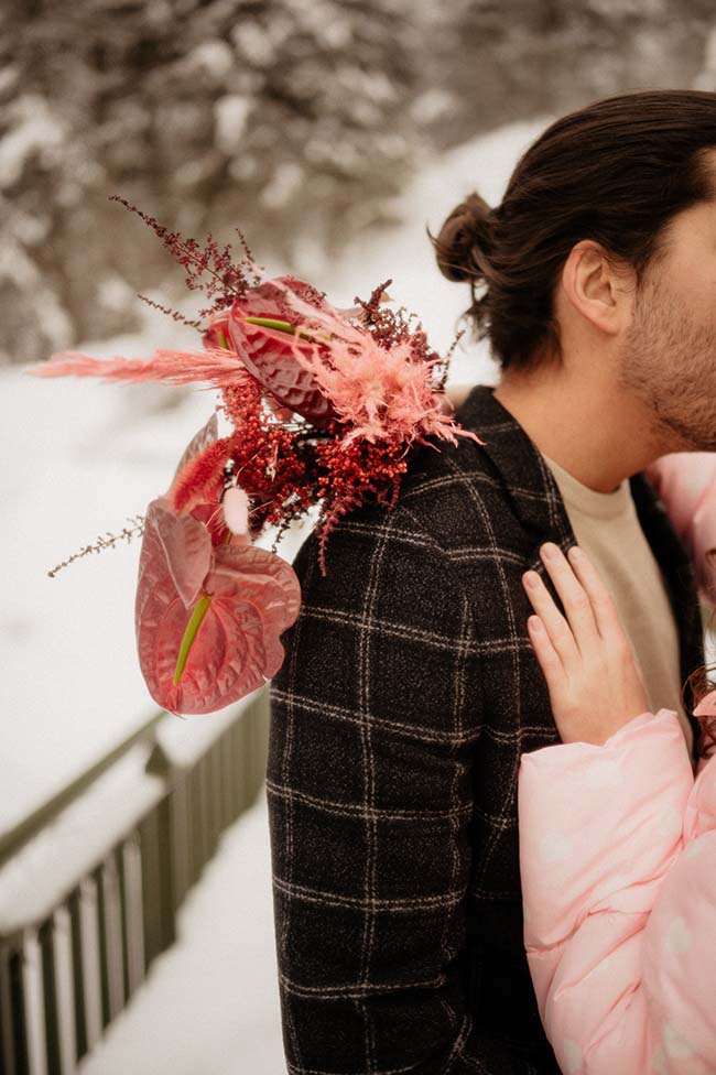 Un couple romantique se détache contre un décor neigeux, vêtu d'un manteau rose chaud et tendre.