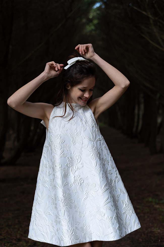 Une jeune femme dans un magnifique jupe blanche ornée de motifs floraux se joue dans un parc serein.