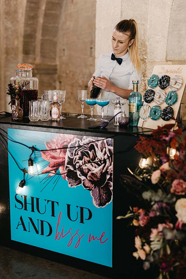 Un bar à cocktails coloré avec une affiche pop et folk inspirée, idéal pour un mariage vibrante et unique.
